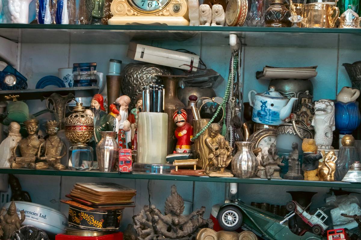Stacked wooden crates filled with antique and estate treasures including porcelain, books, and vintage jewelry at an estate auction preview